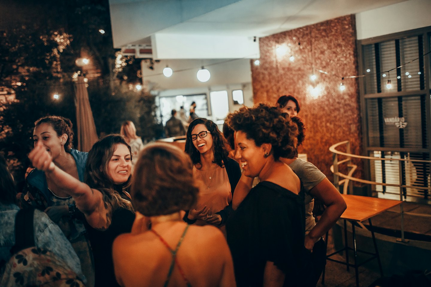 Un grupo de mujeres riendo y charlando juntas en una reunión al aire libre.